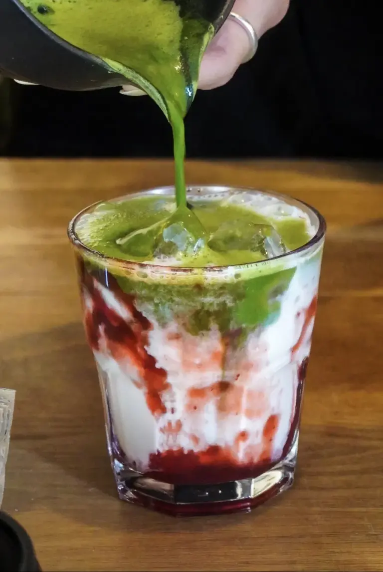 Matcha pilama į stiklinę su braškių uogiene ir pienu